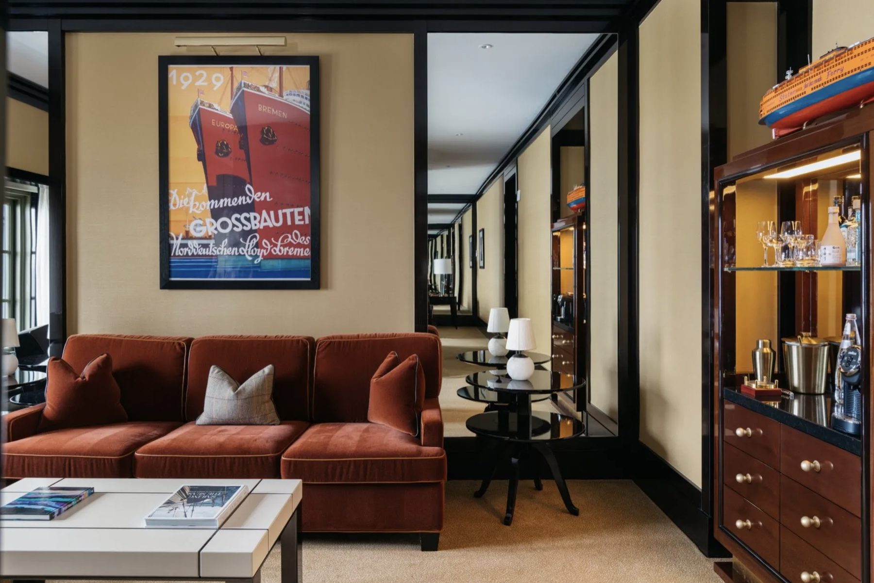 The one-bedroom suite — a warm living room with a bar cabinet, art, and mirrored walls.